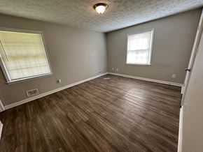 Riverdale house for rent - an empty living room with wooden floors and a window