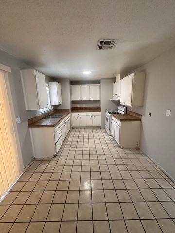La Quinta house for rent - an empty kitchen with white cabinets and tiled floors