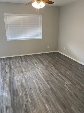 Tucson house for rent - an empty room with wood floors and a ceiling fan