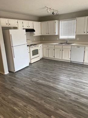 Tucson house for rent - an empty kitchen with white cabinets and a refrigerator