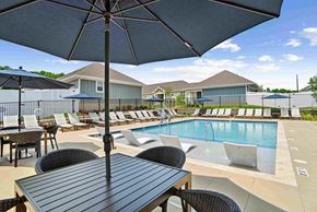 Charlotte triplex for rent - A poolside table with chairs and an umbrella over it. at Zora University, Charlotte, 28213