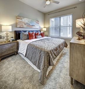 Austin apartment for rent - A bedroom with a large bed and a painting on the wall at Arise Riverside Apartments, Austin, Texas