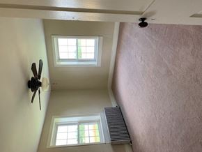 Hummelstown apartment for rent - A ceiling fan is mounted on a white wall in a room with two windows.