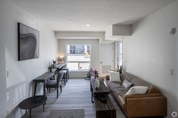 Edmonton apartment for rent - A modern living room with a brown couch and a dining table.