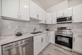 Edmonton apartment for rent - an all white kitchen with stainless steel appliances and white cabinets