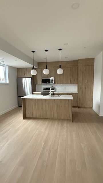 Calgary townhouse for rent - A kitchen with wooden cabinets and a light brown floor.