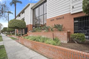 Santa Ana apartment for rent - Bush Terrace is a residential building with a brick wall and green plants.