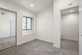 Anaheim apartment for rent - A spacious room with a carpeted floor and a window with blinds.