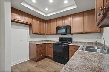 Anaheim apartment for rent - A kitchen with brown cabinets and a black stove top oven.