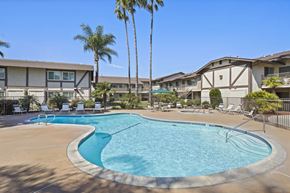 Anaheim apartment for rent - A swimming pool surrounded by palm trees and lounge chairs.