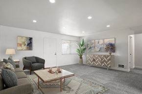 Anaheim apartment for rent - A living room with a grey couch, a brown armchair, a wooden coffee table, and a rug.