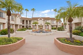 Santa Ana apartment for rent - A courtyard with palm trees and a fountain in the middle of apartment buildings.