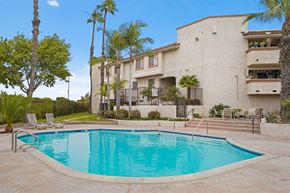 Santa Ana apartment for rent - A swimming pool in front of a building with palm trees.