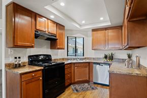 Santa Ana apartment for rent - A kitchen with wooden cabinets and a black stove top oven.
