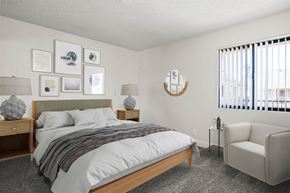 Santa Ana apartment for rent - A bedroom with a bed, chair, and pictures on the wall.