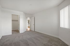 Anaheim apartment for rent - A spacious empty room with carpeted floor and white walls.