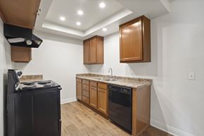 Anaheim apartment for rent - A kitchen with a black fridge, black oven, wooden cabinets and a marble counter top.