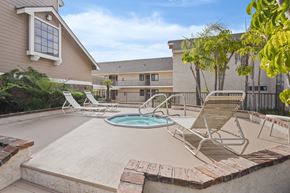 Anaheim apartment for rent - A pool with a hot tub and chairs in front of a house.