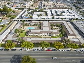 Anaheim apartment for rent - A large building with a pool in the middle of a grassy area.
