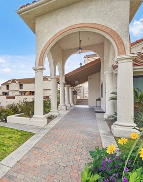 Anaheim apartment for rent - A white archway with a brick pathway leading to a building.