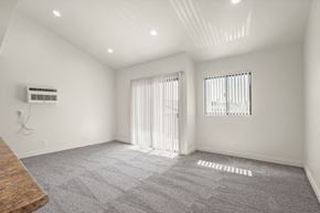 Anaheim apartment for rent - A spacious room with a carpeted floor and two windows with curtains.
