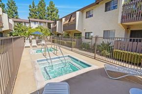 Anaheim apartment for rent - A pool with a slide in the middle of a patio surrounded by a fence.