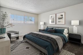 Anaheim apartment for rent - A bedroom with a large bed and a bench.