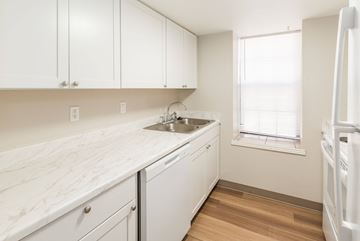 Littleton apartment for rent - A kitchen with white cabinets and a marble countertop.