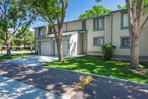 Colorado Springs apartment for rent - A sunny day at a residential area with apartment buildings and green trees.
