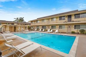 Anaheim apartment for rent - A swimming pool surrounded by sun loungers in front of apartment buildings.