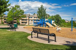 Colorado Springs apartment for rent - A playground with a slide and a bench in the foreground.