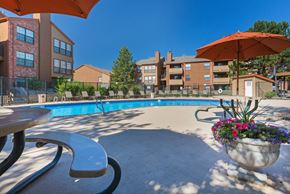 Aurora apartment for rent - A pool area with a table and chairs and umbrellas.