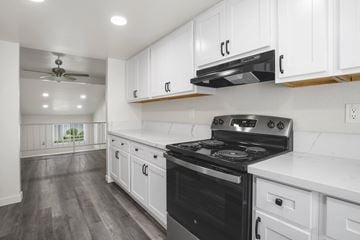 Anaheim apartment for rent - A modern kitchen with a black stove top oven and white cabinets.