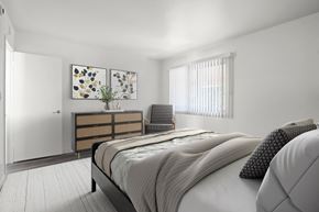 Anaheim apartment for rent - A bedroom with a bed, nightstand, and two paintings on the wall.