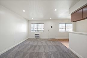 Anaheim apartment for rent - A spacious room with a grey carpet and white walls.