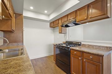 Anaheim apartment for rent - A kitchen with wooden cabinets and a black stove top oven.