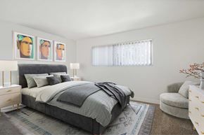 Anaheim apartment for rent - A bedroom with a bed, chair, and three framed pictures on the wall.