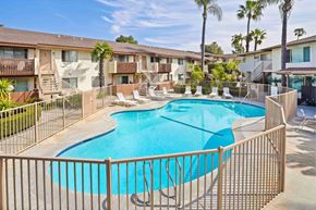 Anaheim apartment for rent - A pool surrounded by a fence and chairs.