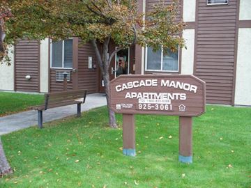 Ellensburg apartment for rent - a wooden sign in the grass in front of a building