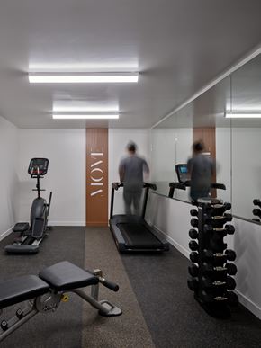 Portland apartment for rent - A gym with a treadmill, a bench and a dumbbell rack.