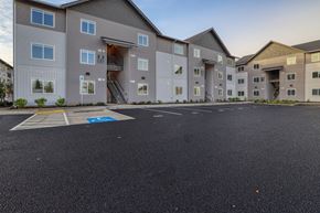 Vancouver apartment for rent - A parking lot in front of a building with a blue handicap parking sign.