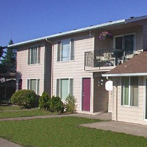 Portland apartment for rent - A beige house with a red door and a balcony with flowers.