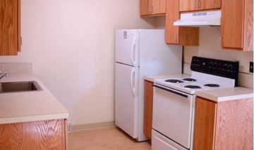 Portland apartment for rent - A white refrigerator and stove in a kitchen with wooden cabinets.