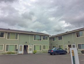 Portland apartment for rent - A car is parked in front of a building with a grey sky in the background.