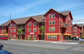 Portland apartment for rent - A red and yellow apartment building with a car parked in front.