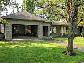 Portland apartment for rent - A small stone building with a porch and a tree in front.