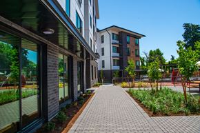 Tigard apartment for rent - a sidewalk in front of a building with trees and plants