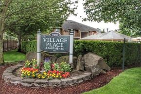 Clackamas apartment for rent - a village place apartments sign in front of a garden and rocks