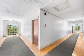 Portland apartment for rent - A long hallway with a red door and a window with a view of trees.