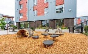 Portland apartment for rent - A playground area with a wooden log and several round tables.